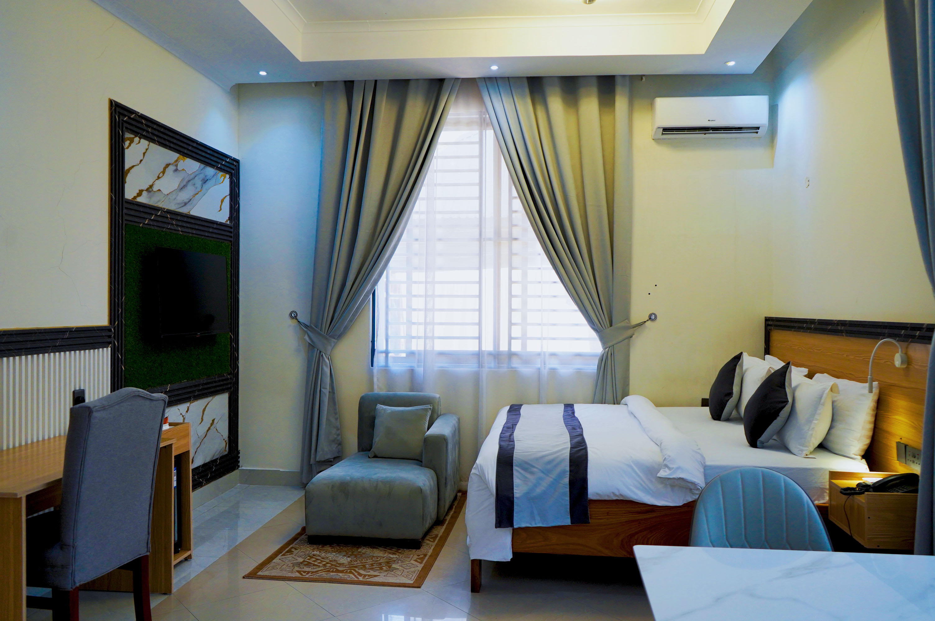 Wide room view showing the bed, armchair, desk and curtained window