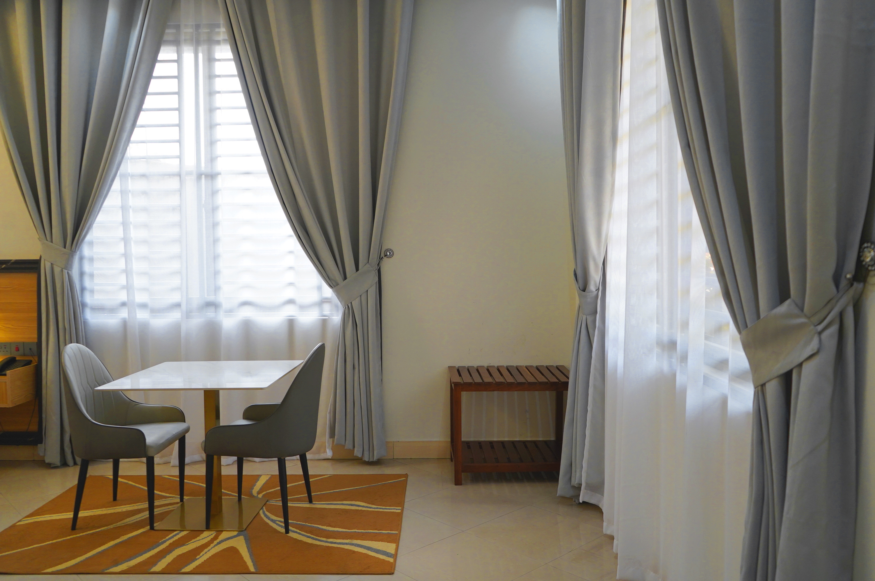 Two chairs and a small table beside wide curtained windows