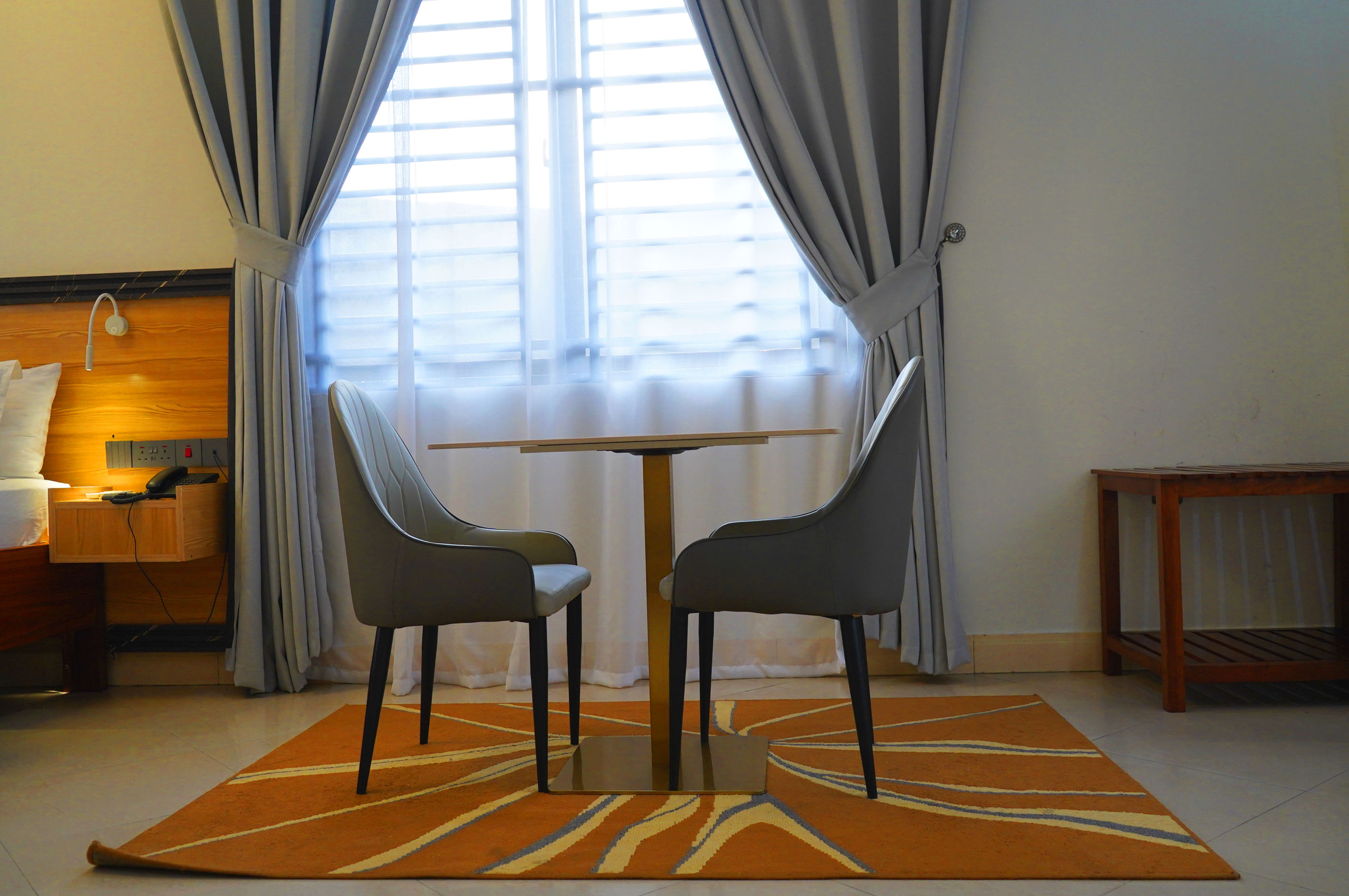 Two dining chairs at a table beside the bed and window